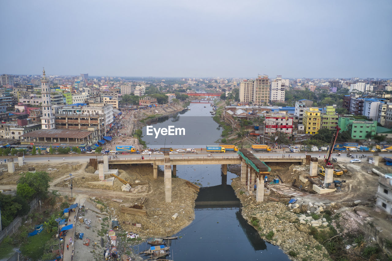 HIGH ANGLE VIEW OF BUILDINGS BY RIVER AGAINST SKY