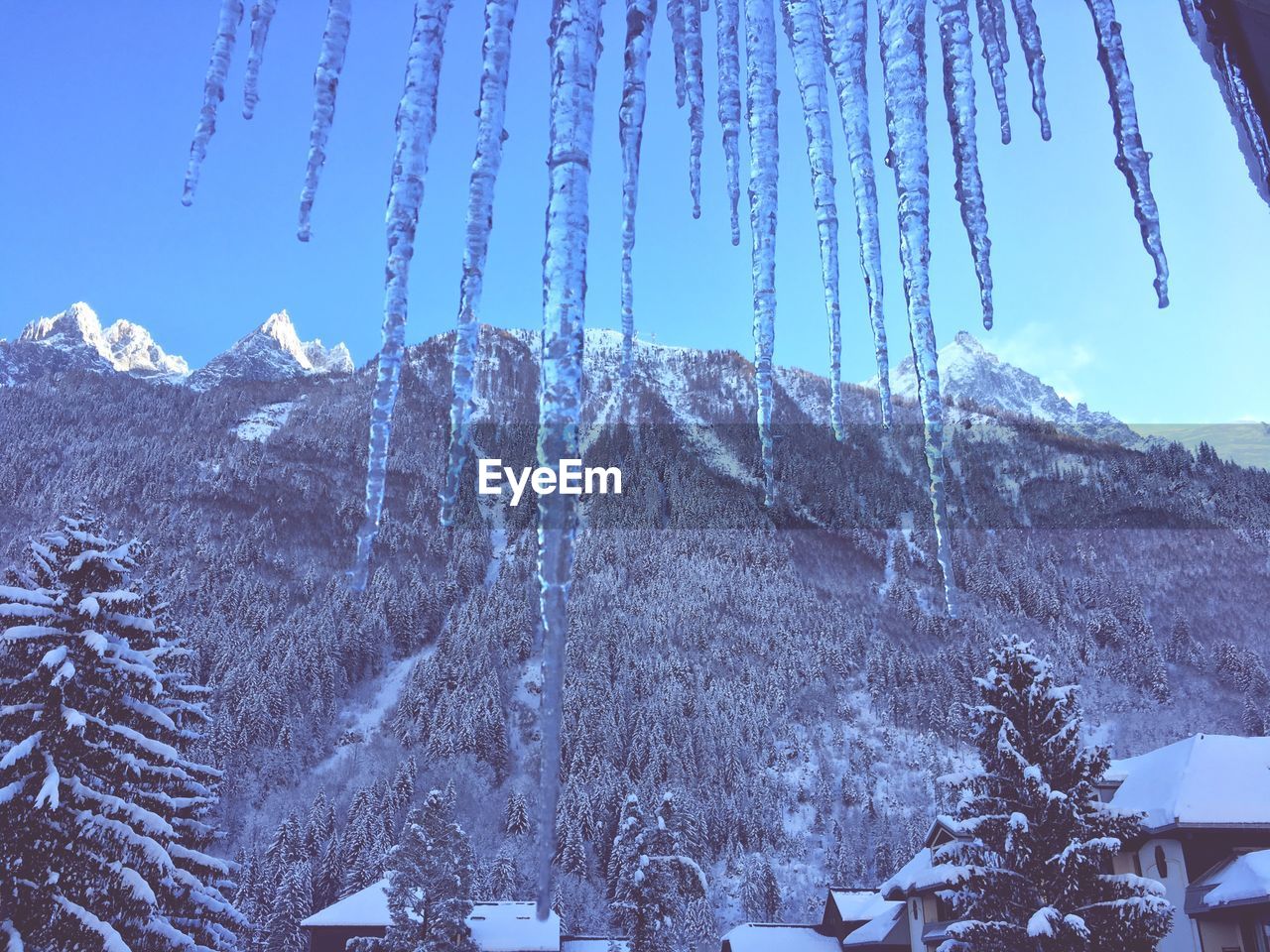 LOW ANGLE VIEW OF ICICLES AGAINST MOUNTAIN RANGE