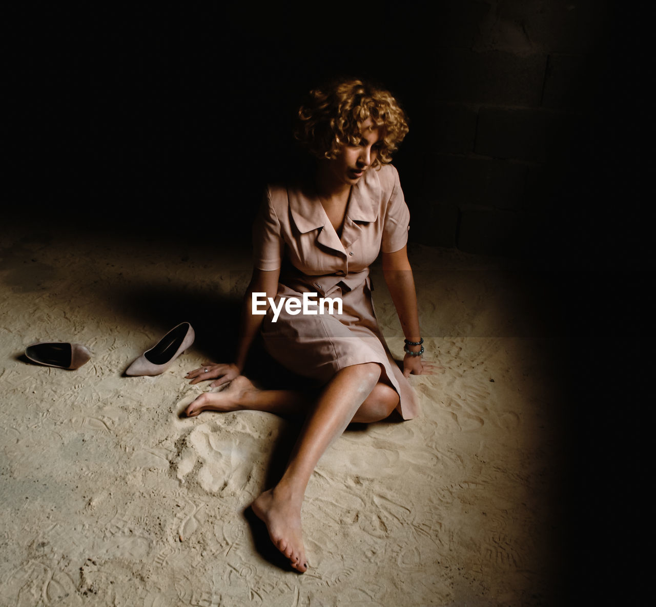 Full length of woman sitting on floor in darkroom