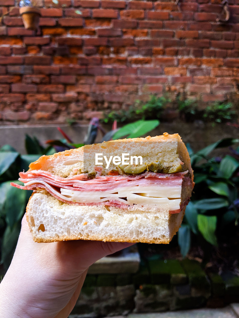 CLOSE-UP OF HAND HOLDING BREAD ON LEAF