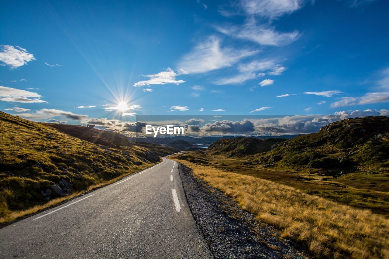 Road leading towards mountains against sky