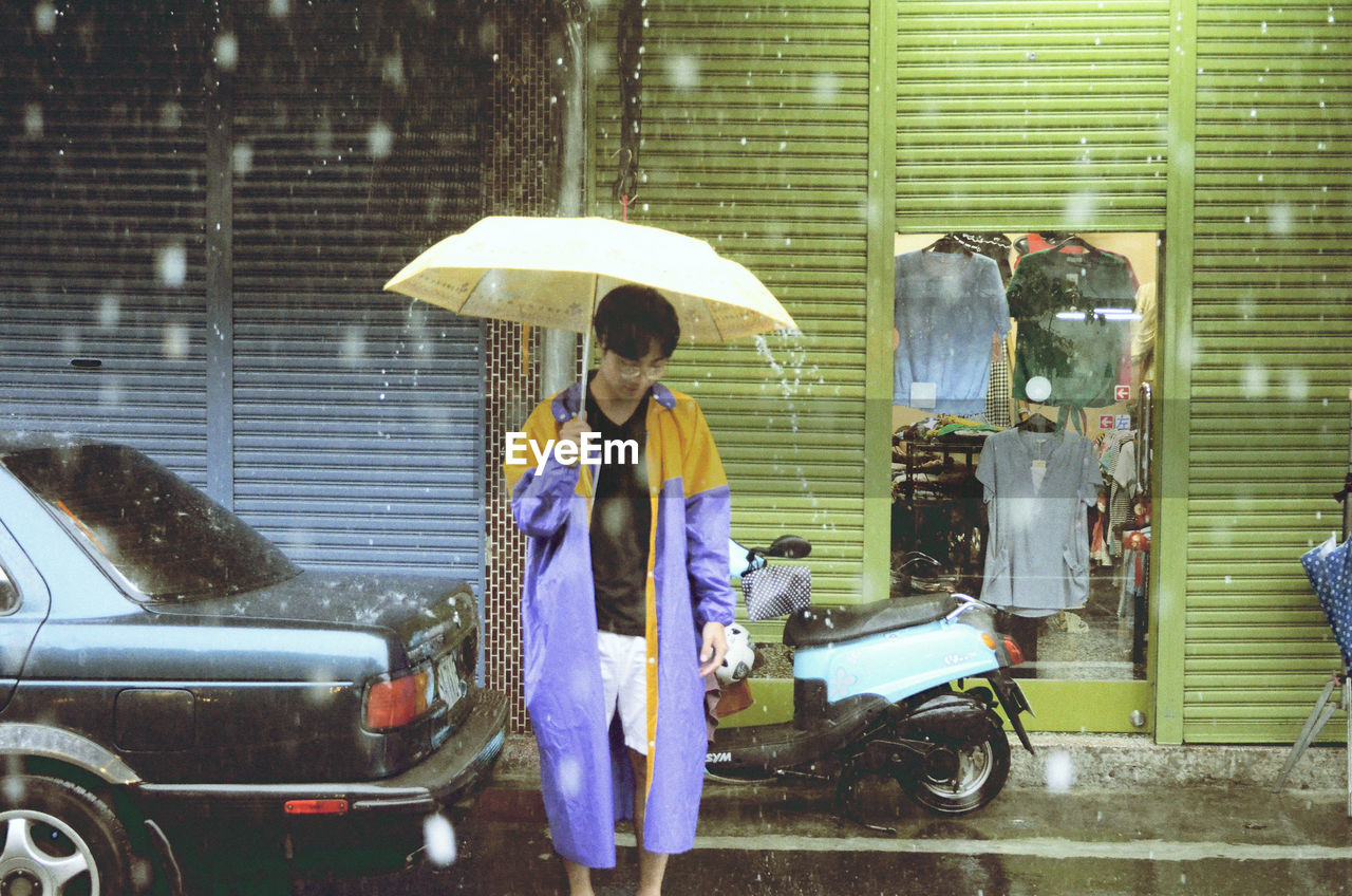 WOMAN WITH UMBRELLA ON WET CAR