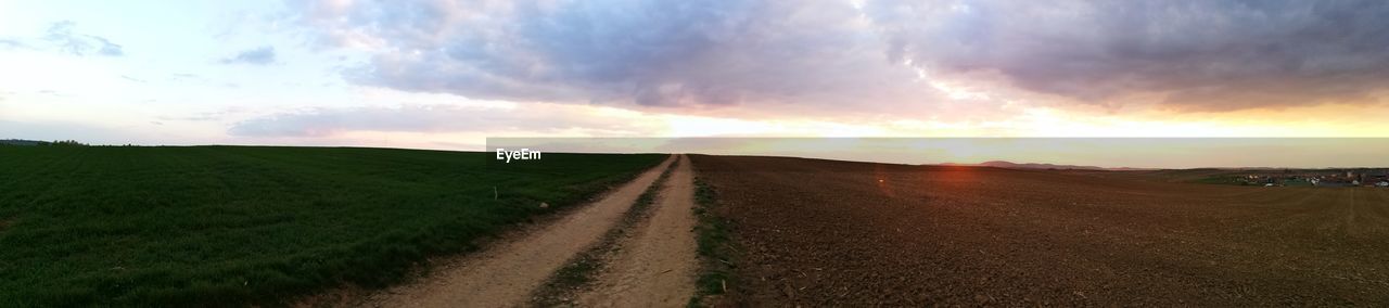 PANORAMIC VIEW OF ROAD AMIDST FIELD AGAINST SKY