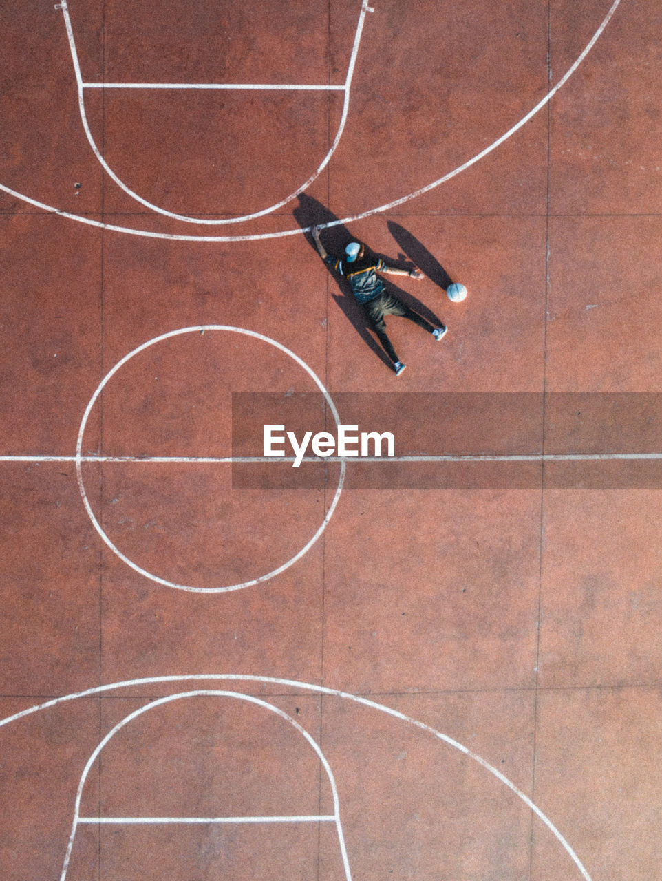 Aerial view of man lying on floor at basketball court