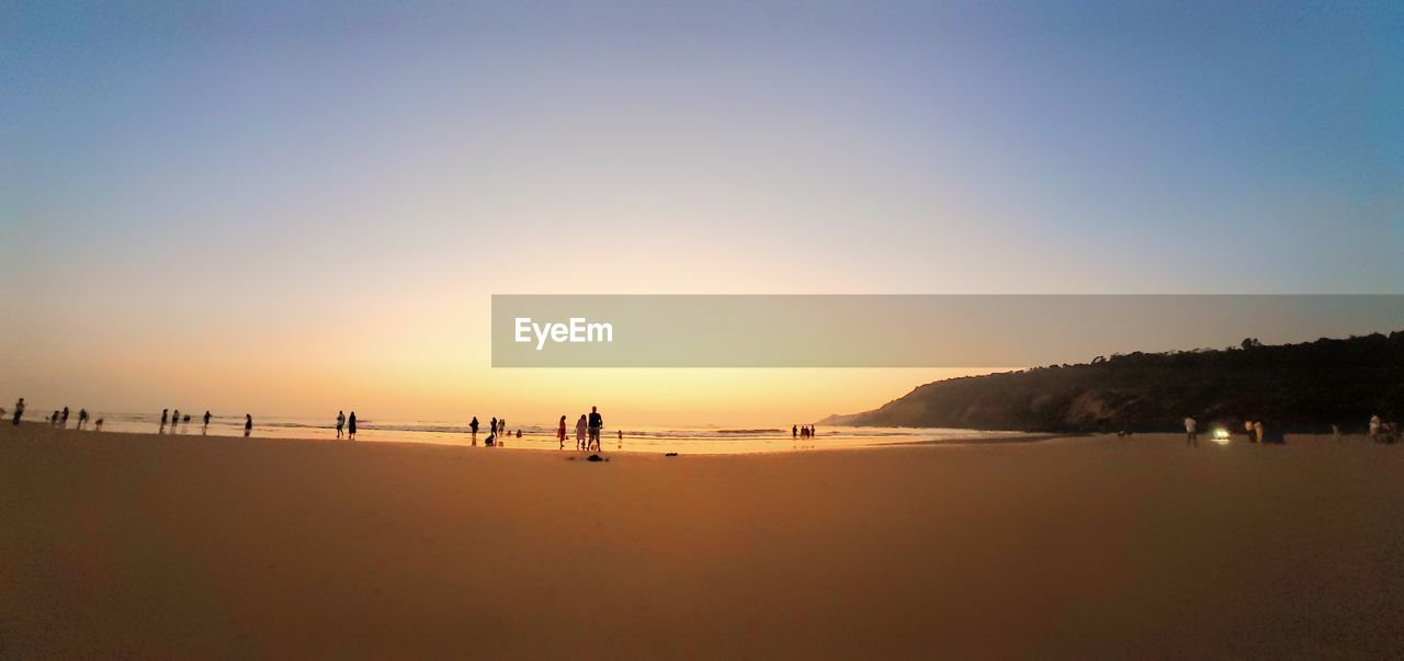 Scenic view of beach against clear sky during sunset