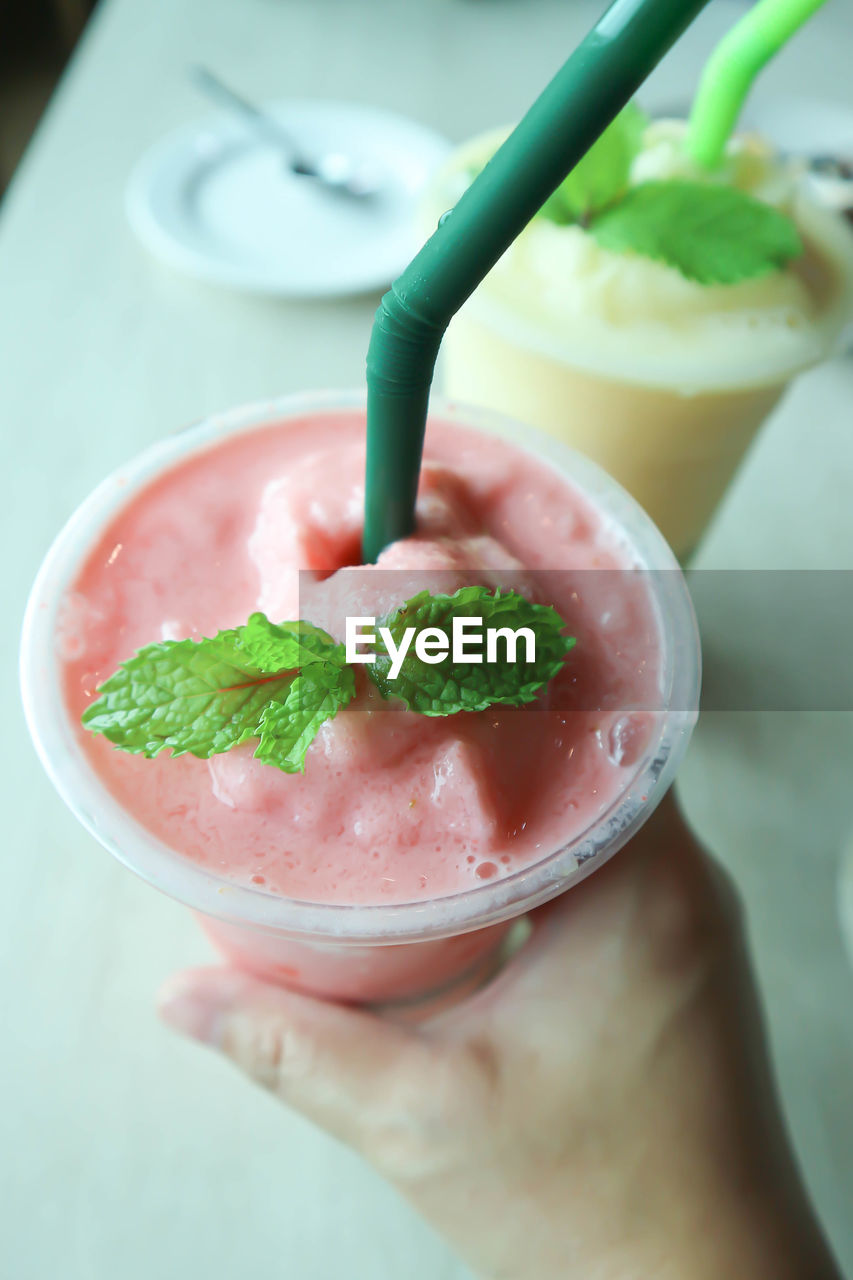 CLOSE-UP OF HAND HOLDING ICE CREAM IN PLATE