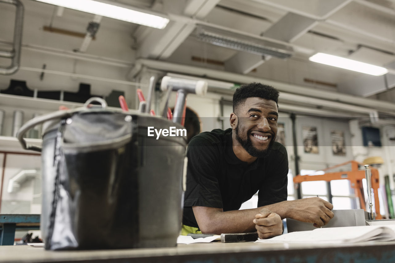 Smiling young male student looking away in workshop