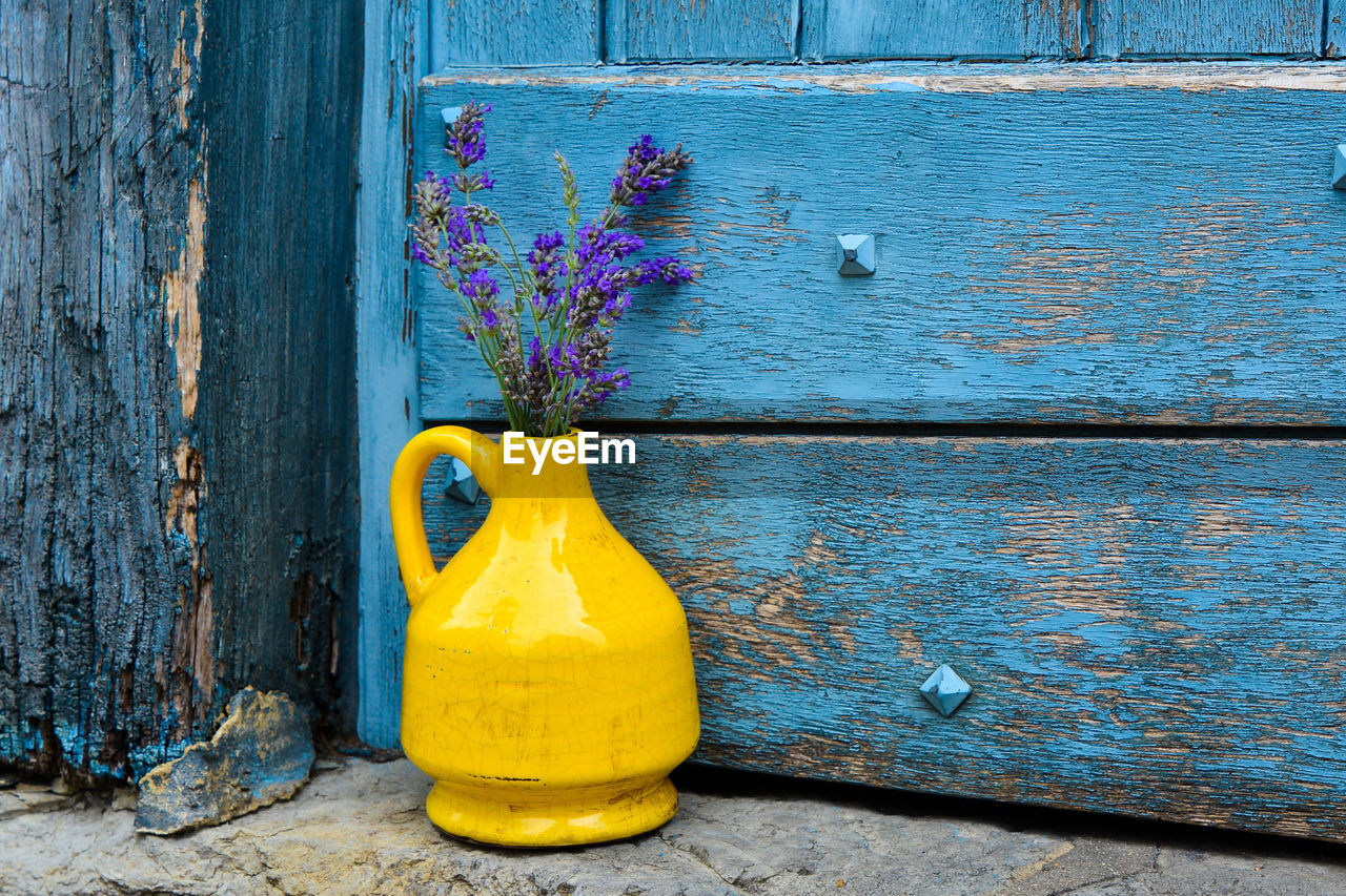 Lavender in a yellow kouvinum on a background of blue shabby door