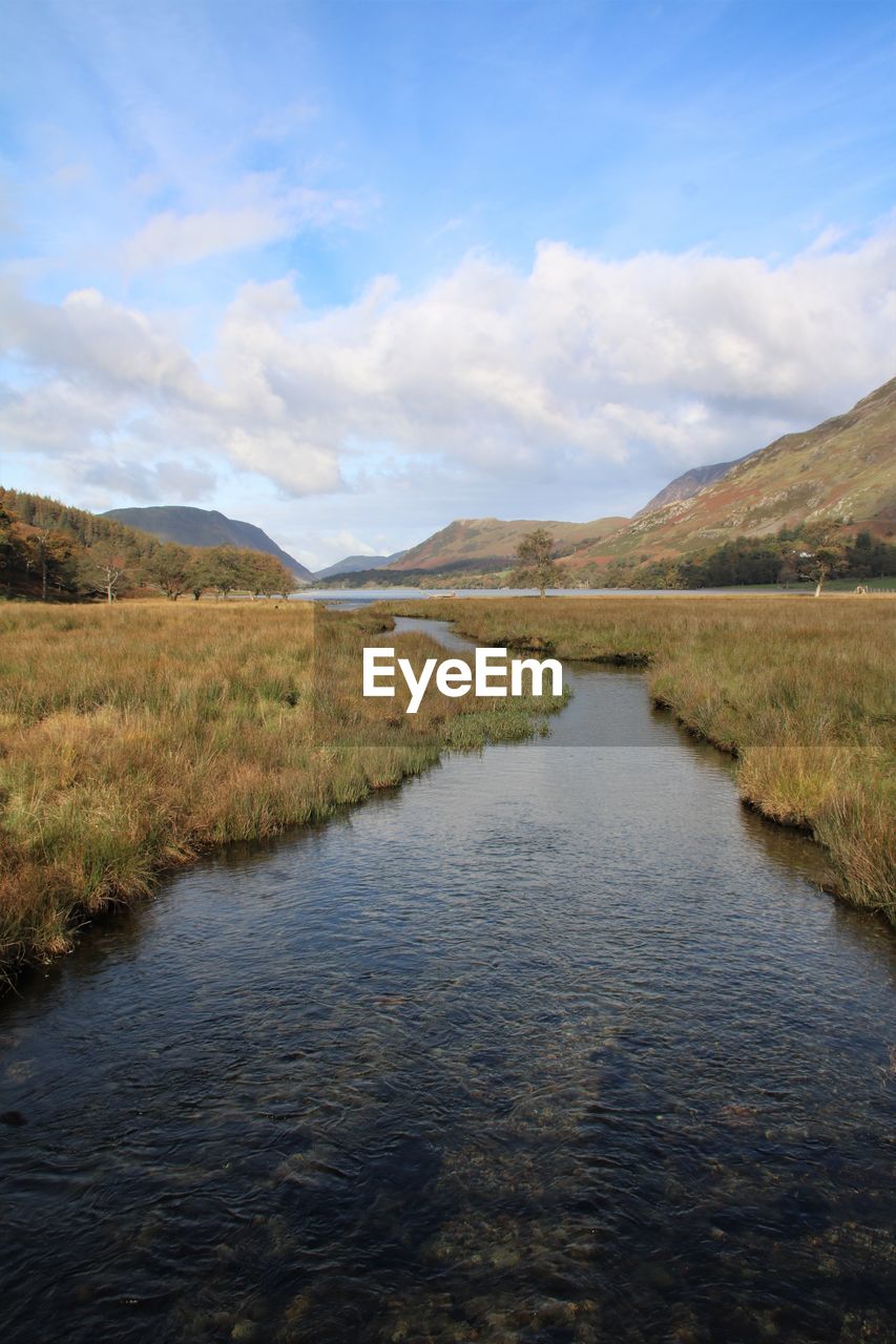 Scenic view of river running into lake against sky