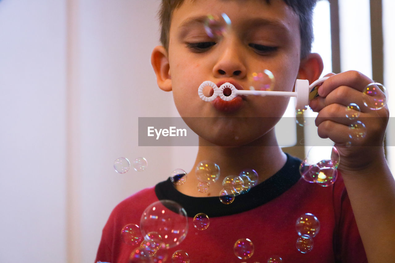 Close-up boy blowing bubbles at home