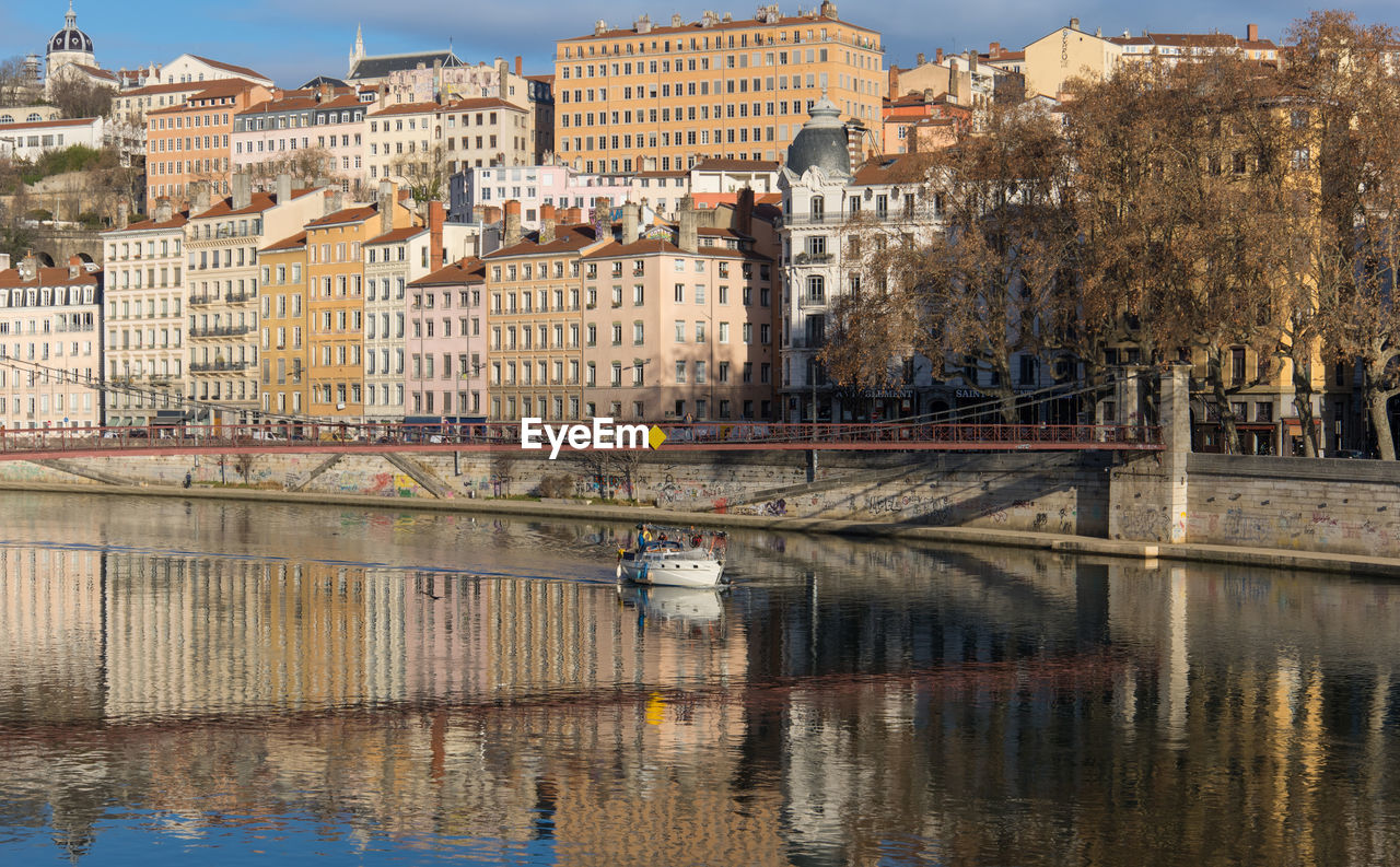 Pleasure boat sailing on the saône in lyon with the old colorful buildings reflecting in the river