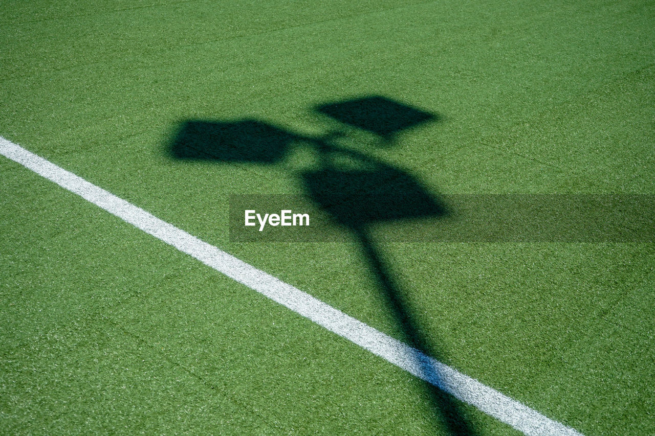 HIGH ANGLE VIEW OF SHADOW OF PERSON ON GREEN BALL