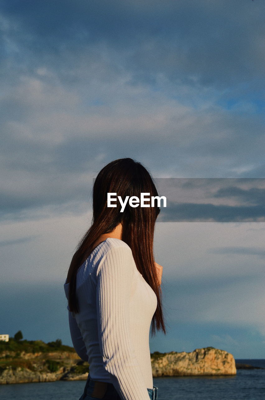 Side view of woman looking at sea against sky