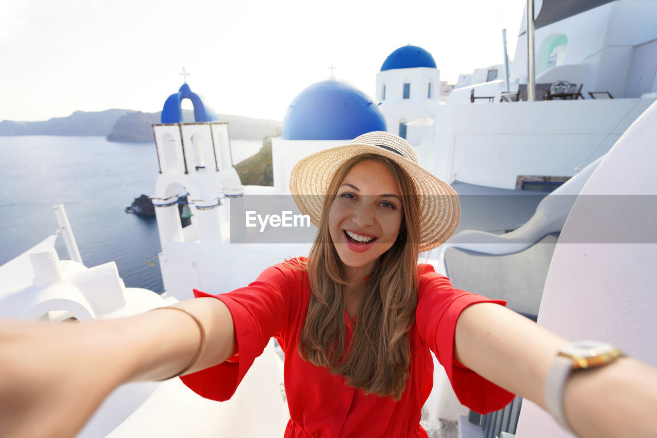 Excited traveler girl taking selfie photo in santorini on sunset