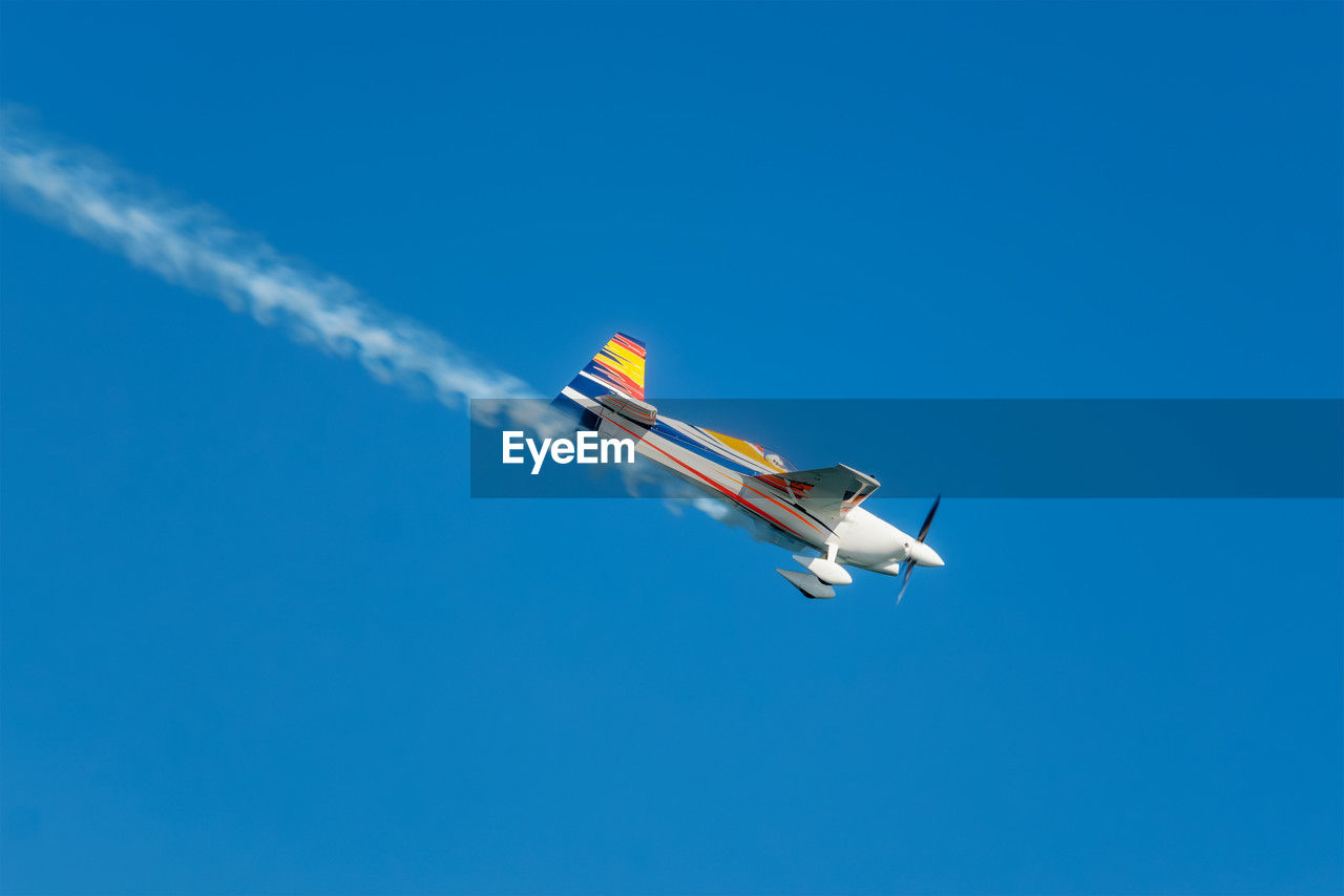 air vehicle, flying, airplane, transportation, mode of transportation, blue, sky, on the move, aerobatics, general aviation, aircraft, motion, vapor trail, vehicle, nature, aviation, air show, clear sky, no people, monoplane, air travel, mid-air, cloud, smoke, wing, copy space, day, speed, travel, outdoors, sunny, low angle view, air force