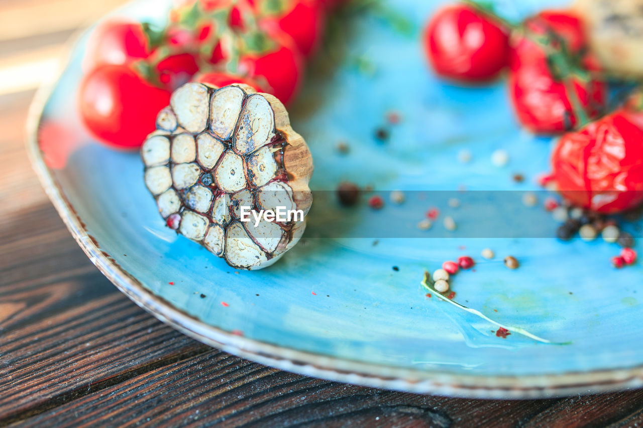 High angle view of garlic and tomato in plate on table