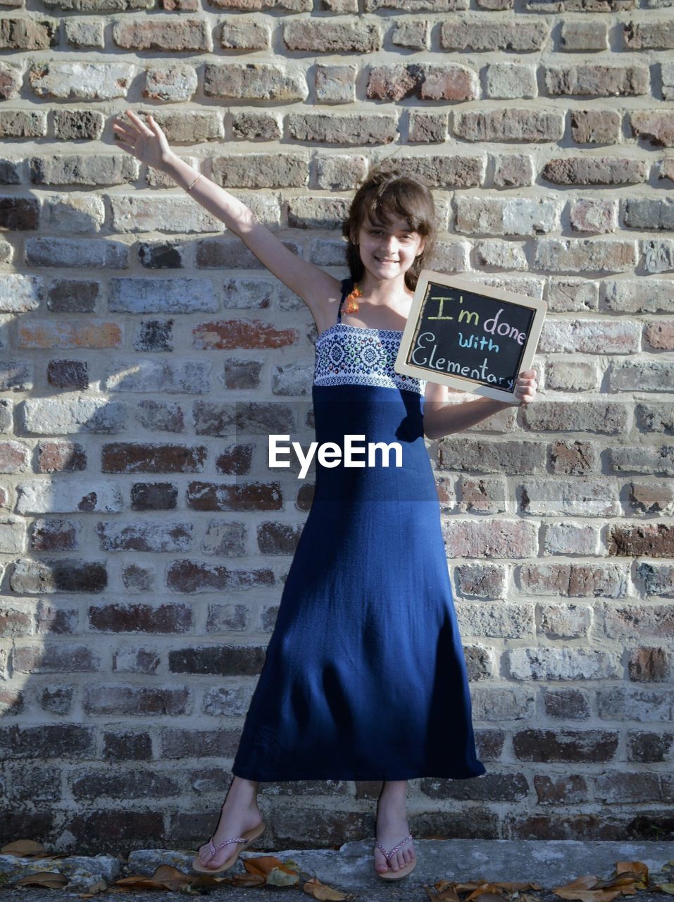 Portrait of smiling girl with message standing against brick wall