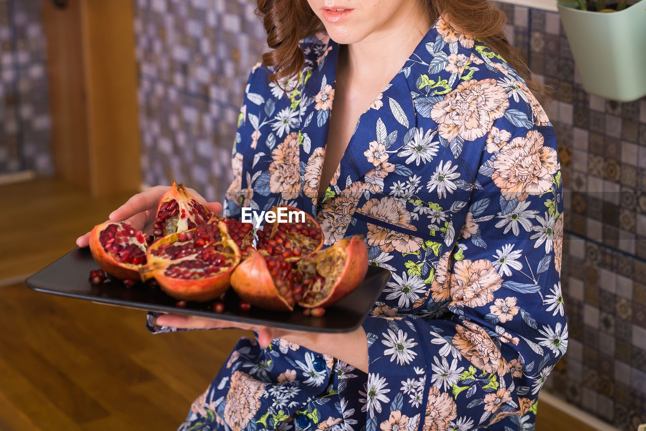 Midsection of woman holding pomegranate