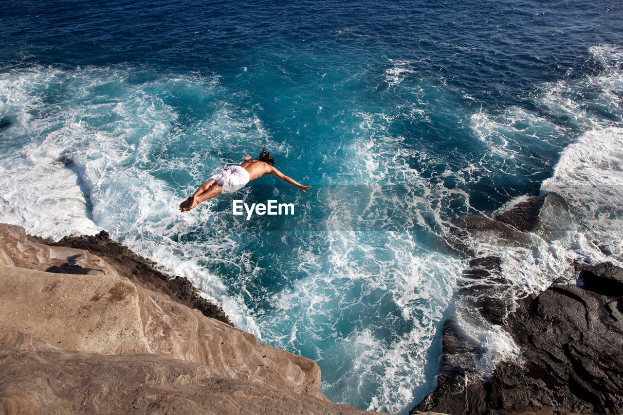 HIGH ANGLE VIEW OF PERSON SWIMMING ON ROCKS