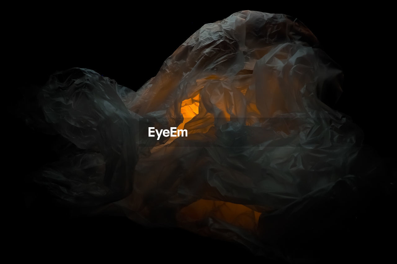 Close-up of burning candle against black background