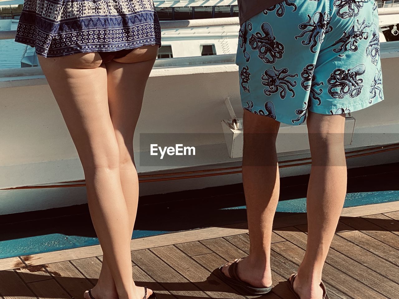 Low section of man and woman standing on pier by yacht