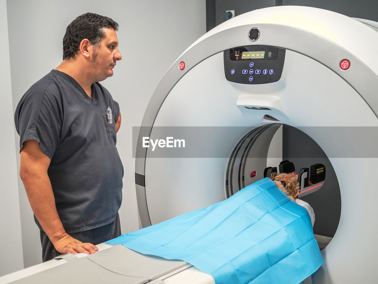 Side view of adult man operating mri scanner during pet examination in contemporary vet clinic