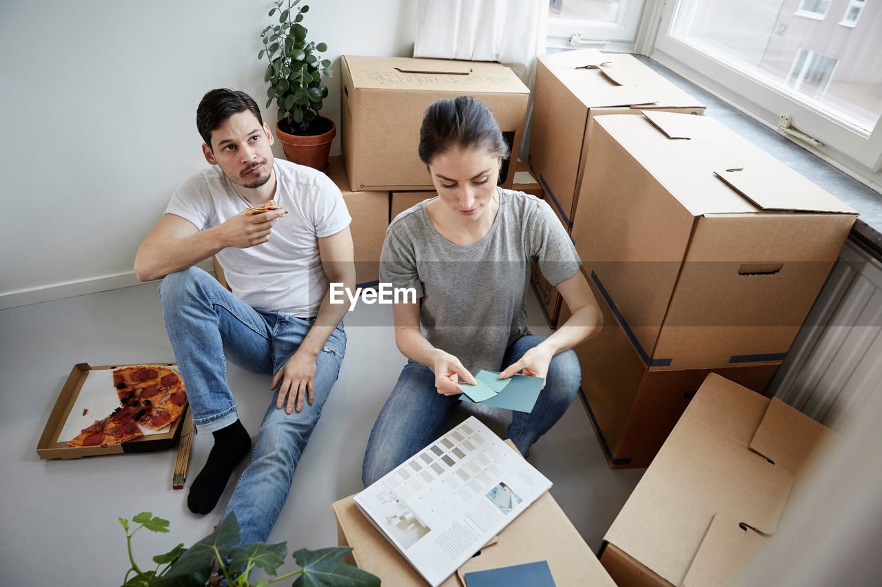 Thoughtful couple with pizza and color swatches during new home relocation