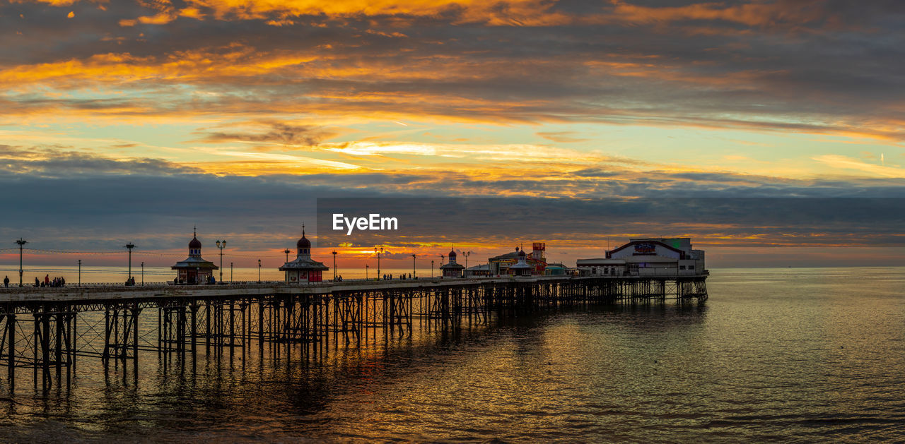 silhouette pier over sea against sky during sunset