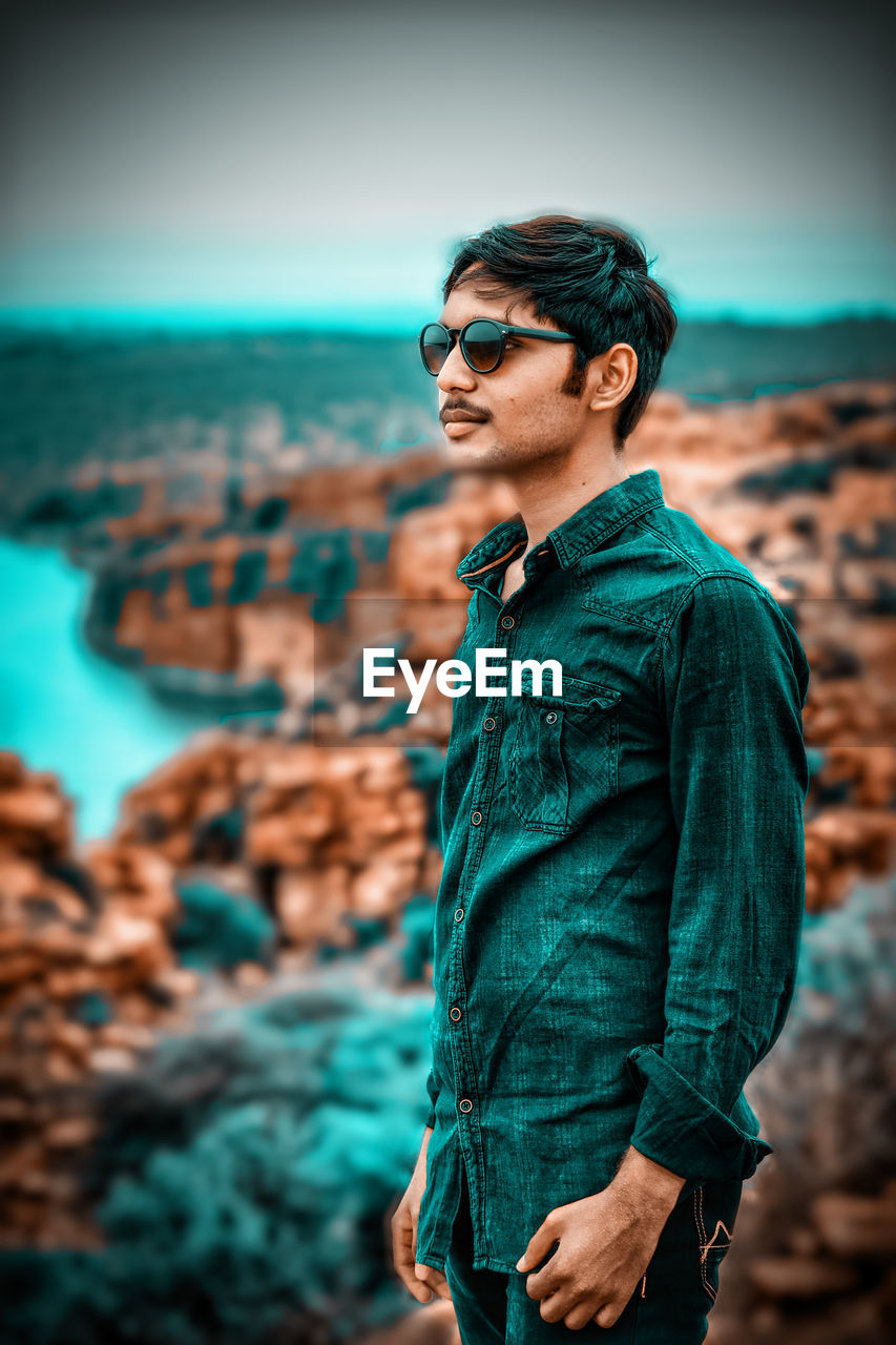 Young man wearing sunglasses standing on beach