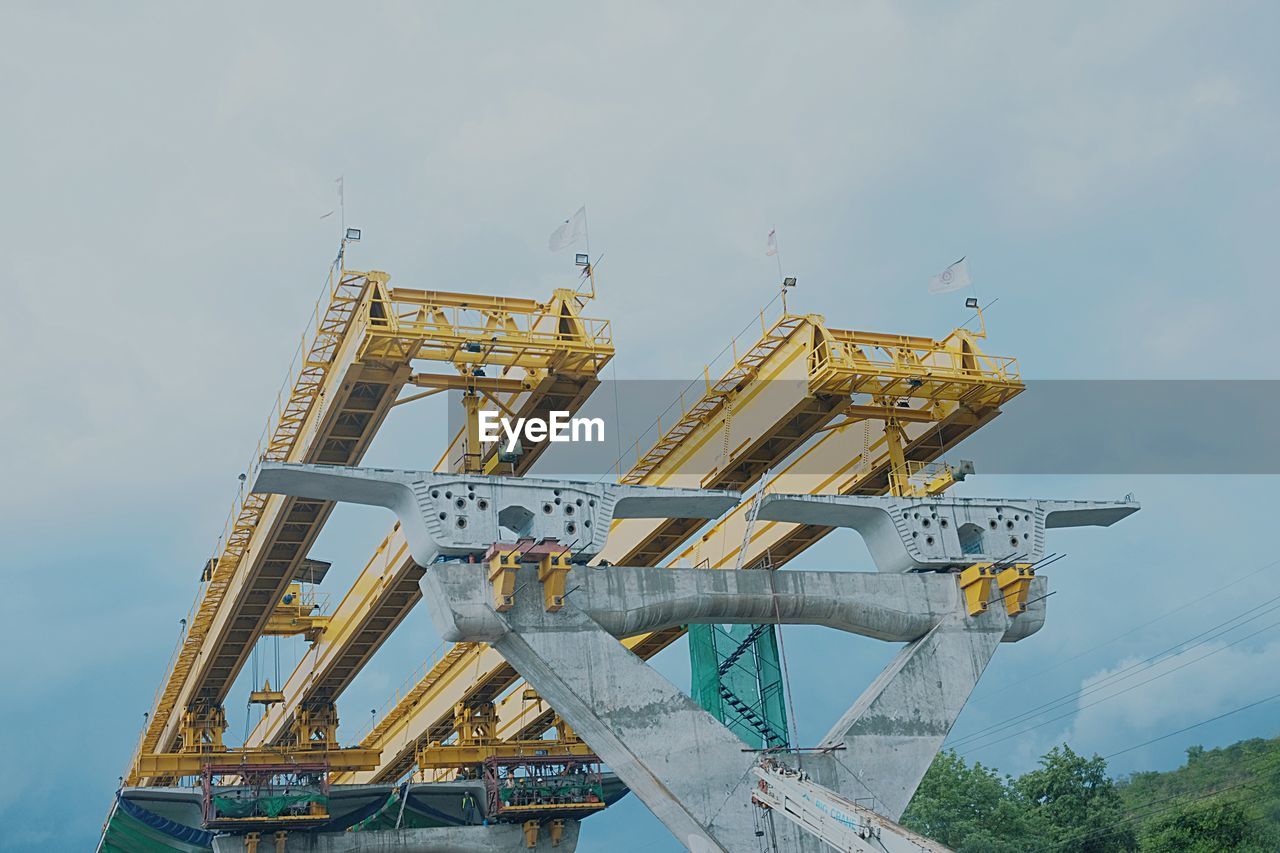 LOW ANGLE VIEW OF CRANES AT CONSTRUCTION SITE AGAINST SKY