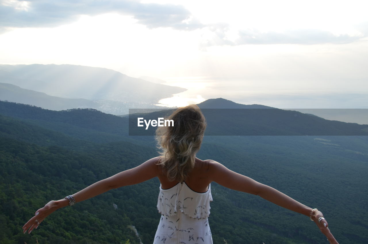 Rear view of wife standing on mountain against sky