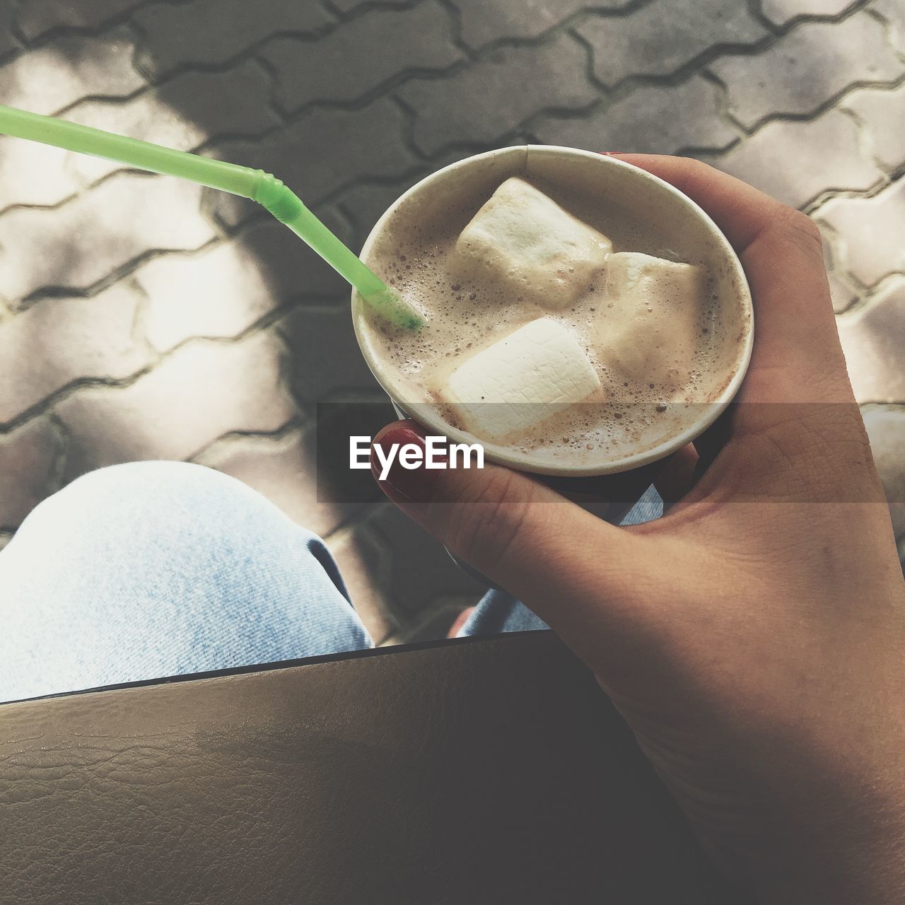 Cropped image of woman hand holding hot chocolate with marshmallows in cup