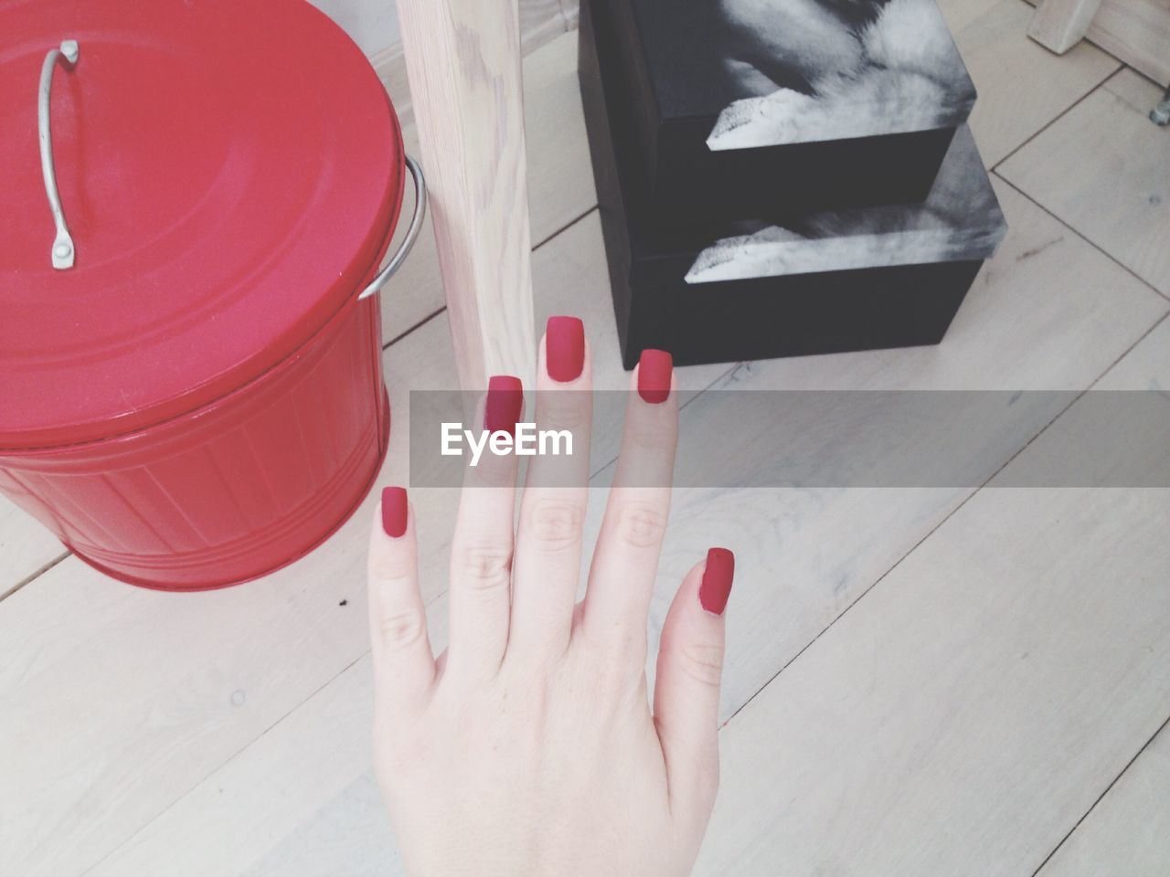 Cropped image of woman hand against red container at home