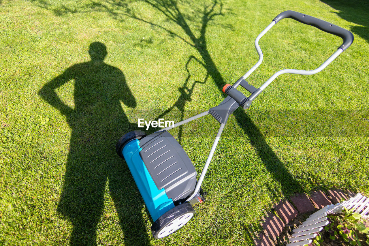 grass, lawn, shadow, sunlight, plant, nature, green, high angle view, leisure activity, day, lawn mower, men, mower, lifestyles, outdoors, one person, adult, golf club, growth, outdoor power equipment, gardening equipment, front or back yard, field, golf, golf course, full length, activity, standing