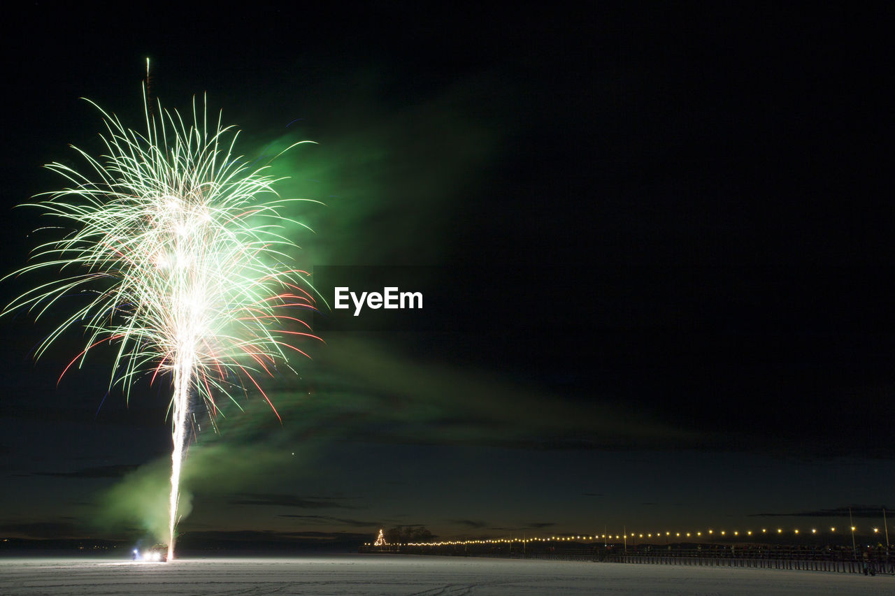 Firework exploding over landscape against sky at night