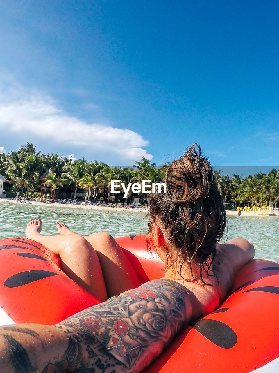 Young woman floating on inflatable ring in sea against blue sky