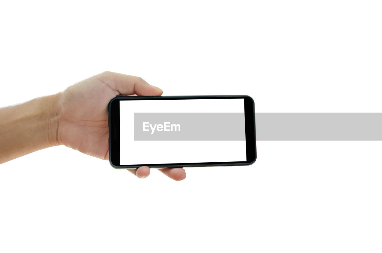 Cropped hand of person holding smart phone against white background