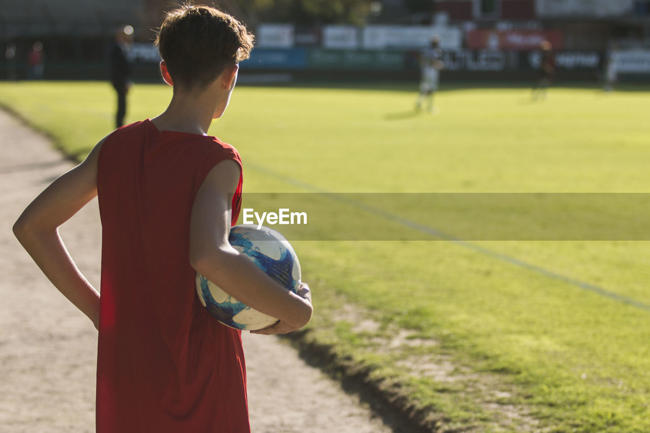 Rear view of man with ball standing on playing field