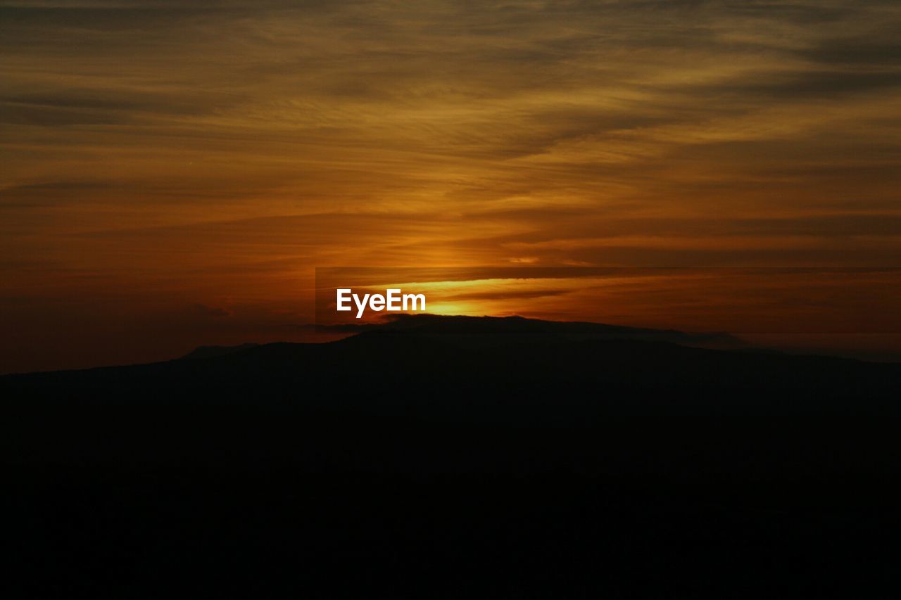 SCENIC VIEW OF SILHOUETTE MOUNTAIN AGAINST SUNSET SKY