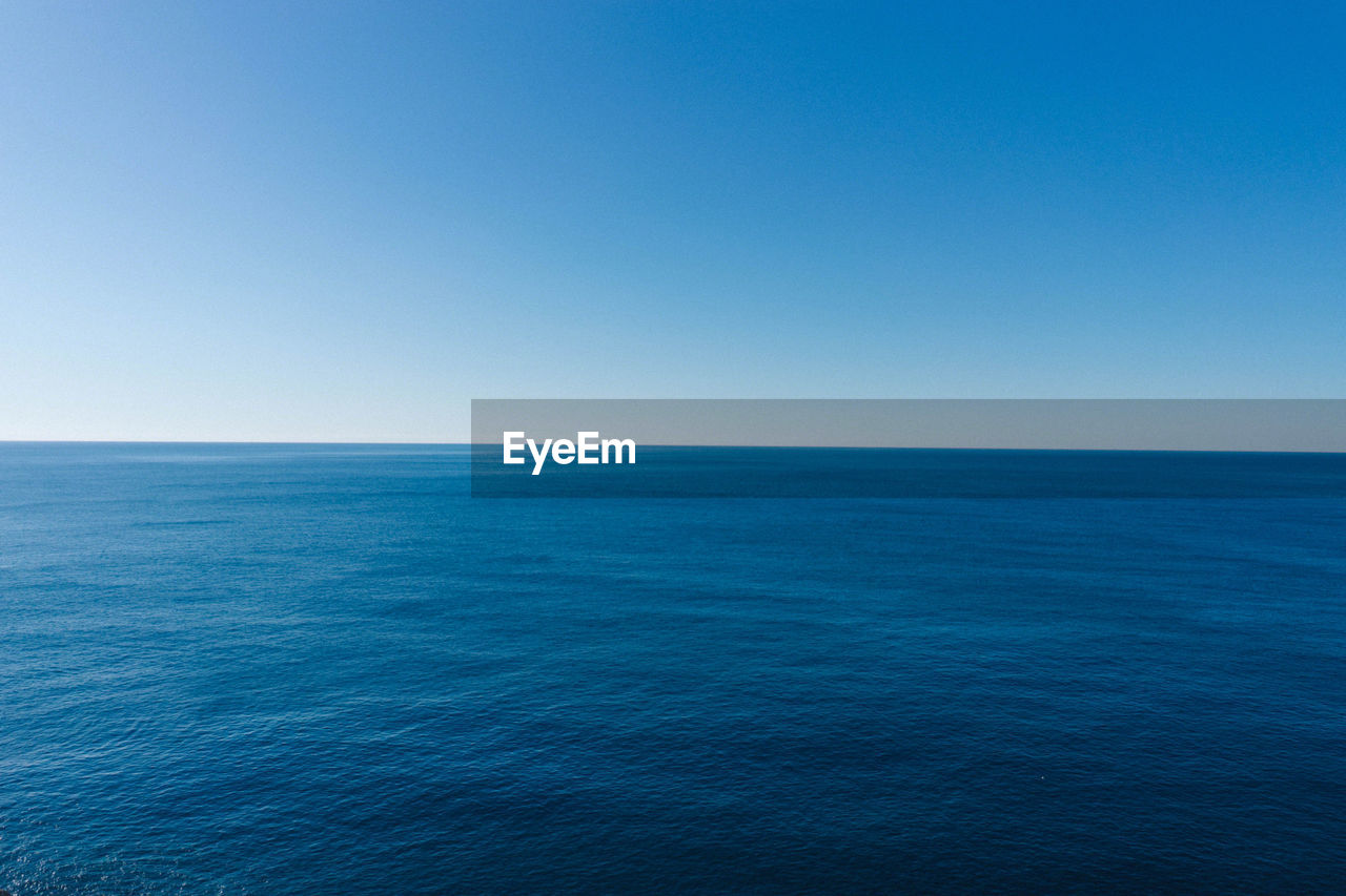 SCENIC VIEW OF SEASCAPE AGAINST CLEAR BLUE SKY