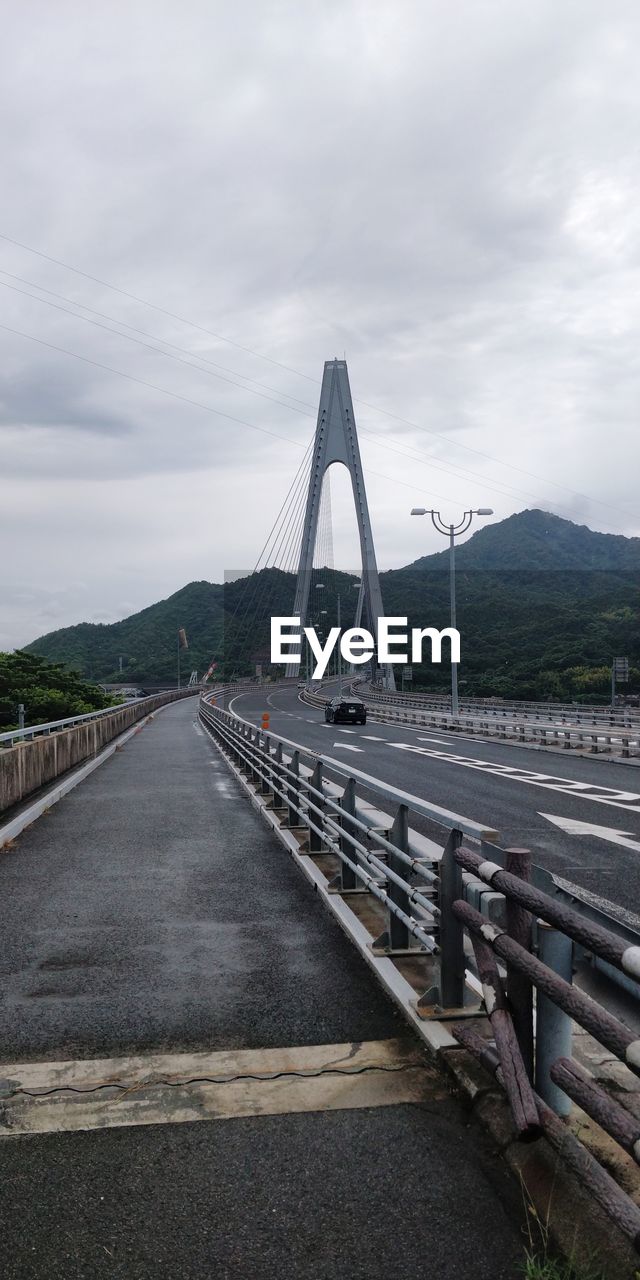 View of suspension bridge against cloudy sky