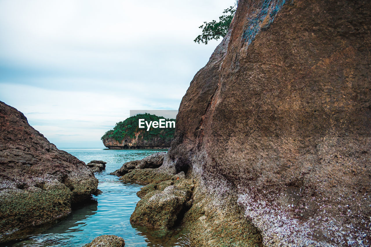 ROCK FORMATION ON SEA AGAINST SKY