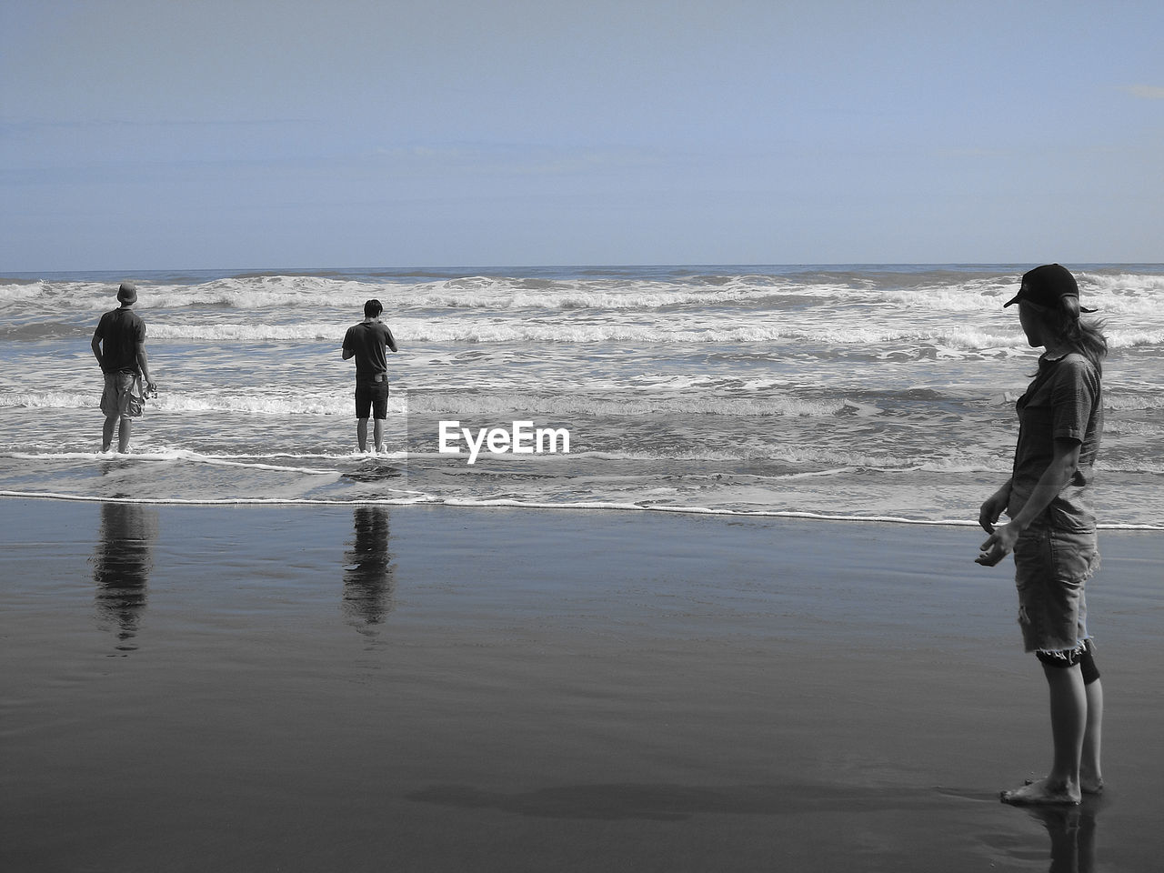 MEN WALKING ON SHORE AGAINST CLEAR SKY