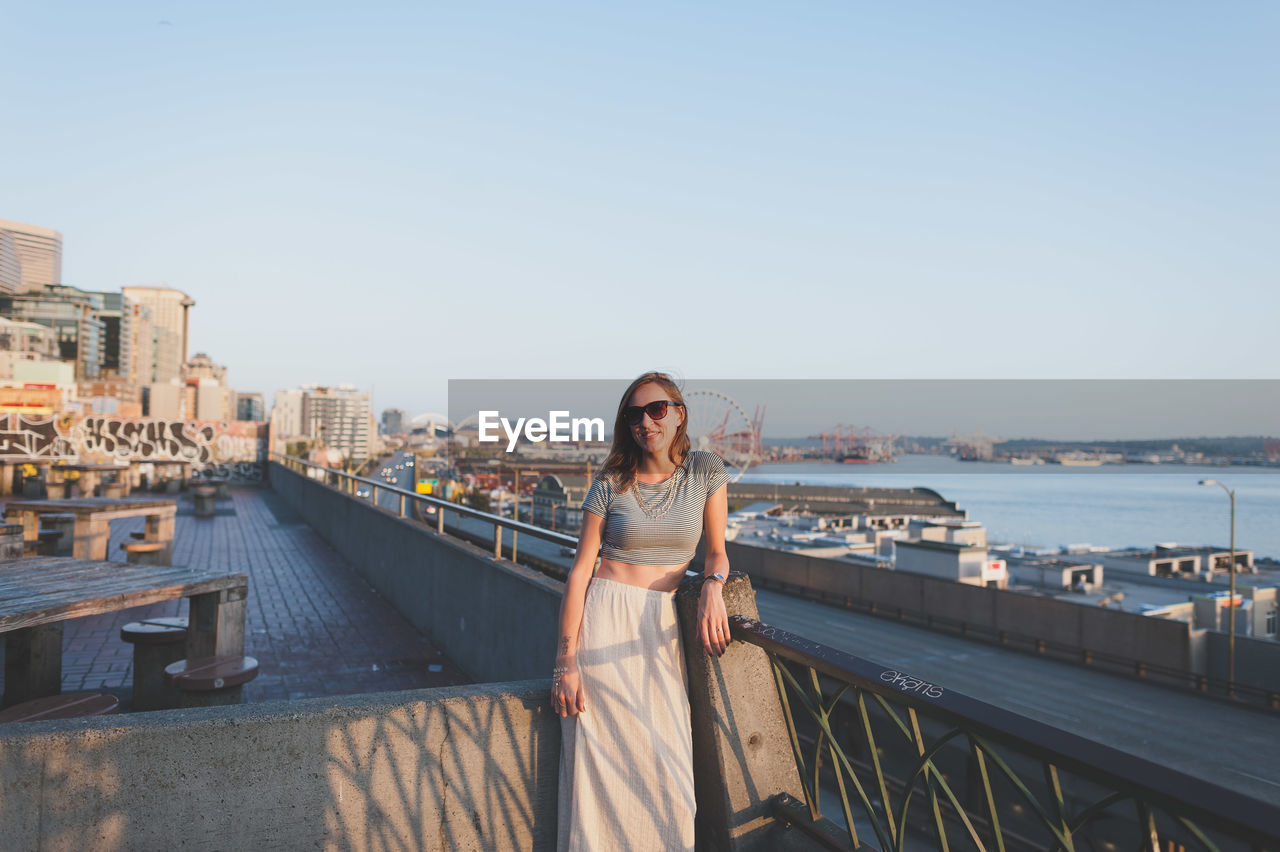 Woman standing by railing against sky