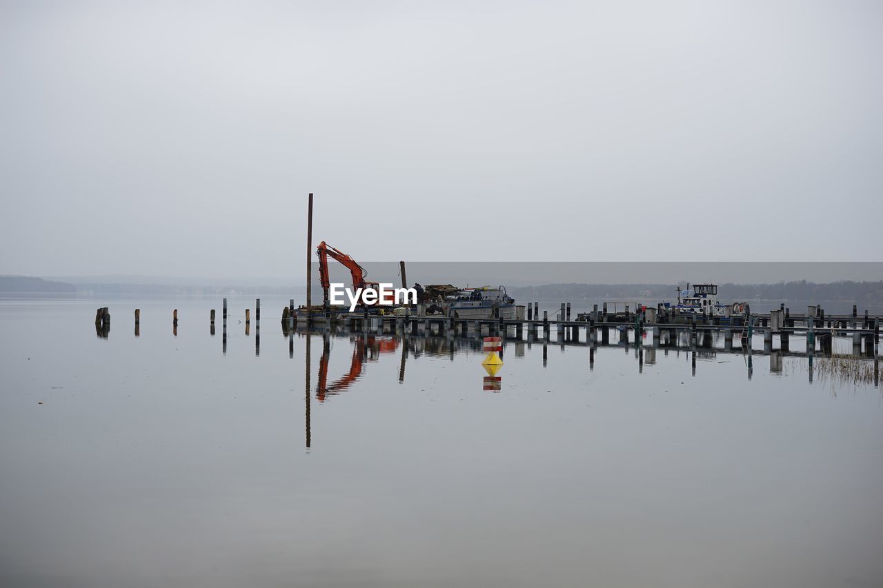 WOODEN POST IN SEA AGAINST SKY