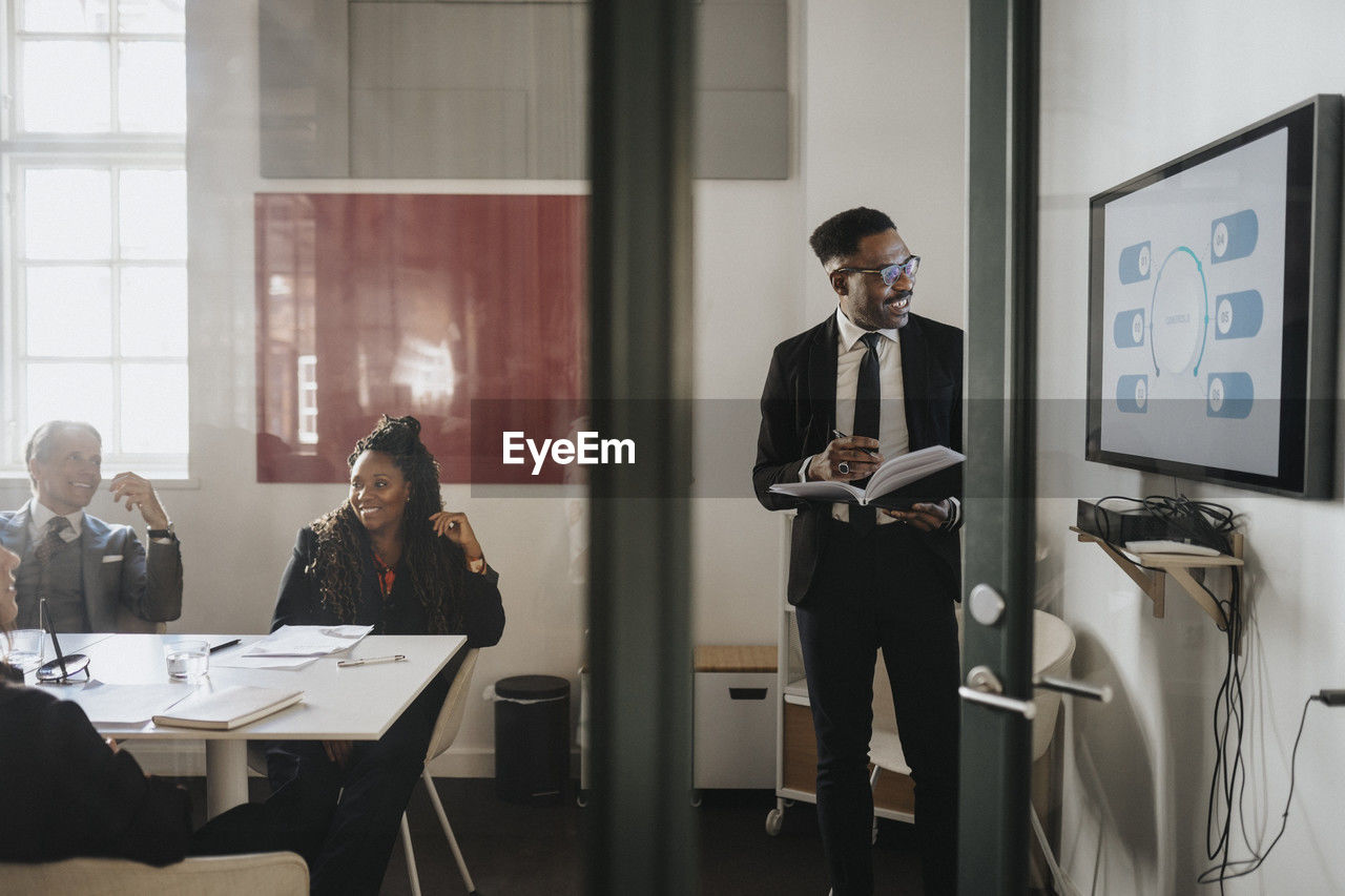 Male and female business colleagues discussing over presentation in board room at office