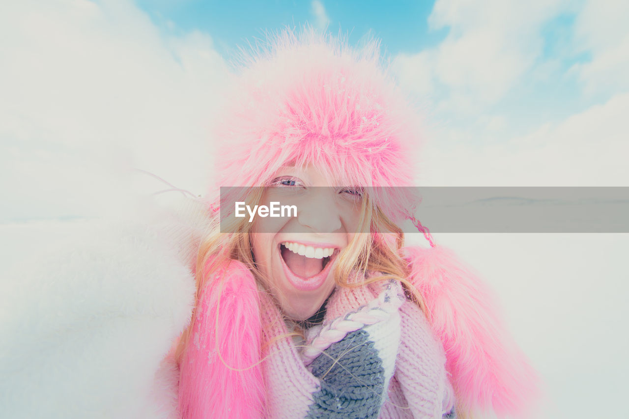 Portrait of young woman with pink hat against sky