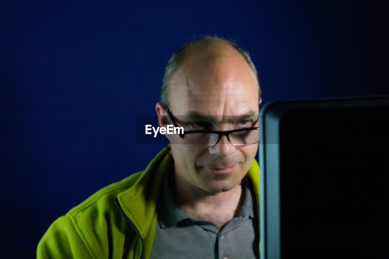 Smiling man using computer against wall at home