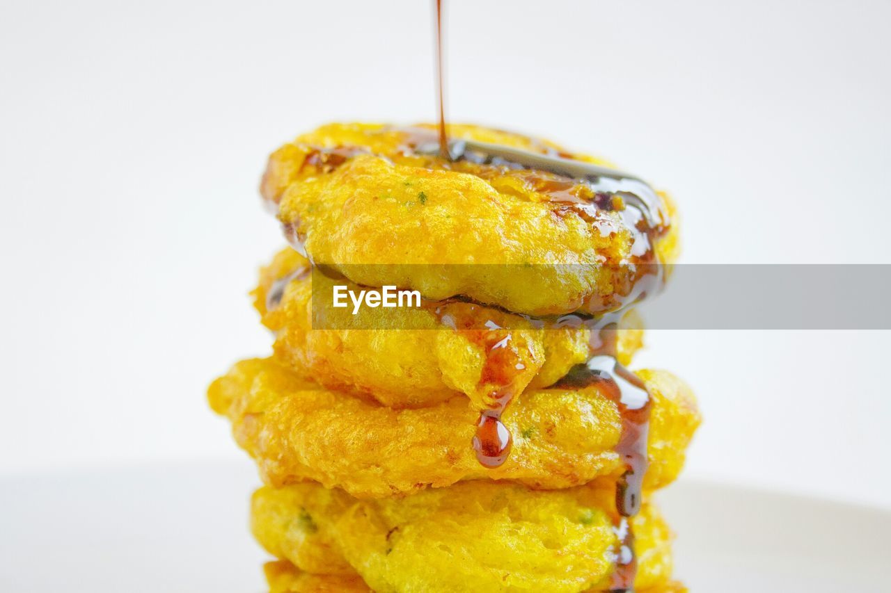 Close-up of omelets with poured honey against white background