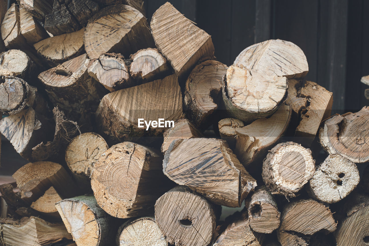 Firewood stocked for home fireplaces in an outdoor wood storage area cross section of a tree trunk